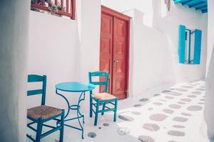 Blue chairs and table on street of typical greek traditional village with white houses on Mykonos Island, Greece, Europe photo