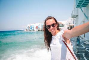 joven hermosa mujer tomando selfie con teléfono al aire libre casa blanca de fondo foto