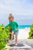 una niña linda lava la arena de sus pies en una playa tropical