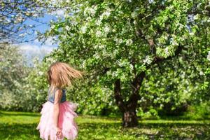 Adorable little girl in blossoming apple garden photo