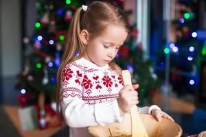 Adorable little girl baking gingerbread cookies for Christmas at kitchen photo