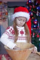 Adorable little girl baking gingerbread cookies for Christmas photo