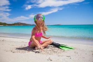 Little girl with flippers and goggles for ssnorkling on the beach photo