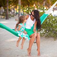 Young mommy and little girl on tropical vacation relaxing in hammock photo