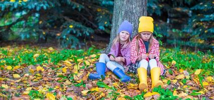 Two adorable girls in forest at warm sunny autumn day photo