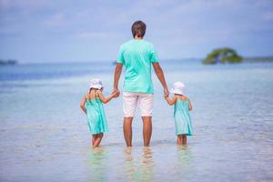 vista trasera del joven padre y sus dos adorables hijas en unas vacaciones exóticas foto