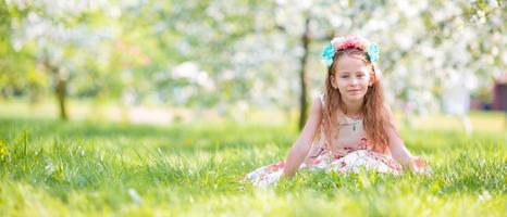 adorable niña en el floreciente jardín de cerezos el día de primavera foto