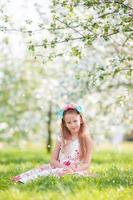 Portrait of little girl in blooming apple tree garden outdoors photo