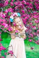 Adorable little girl enjoying smell in a flowering spring garden photo