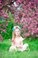 Beautiful little girl in blooming apple tree garden outdoor photo