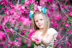 Portrait of adorable little girl in in blooming apple tree garden on spring day photo