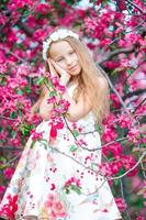 Adorable little girl in in blooming apple tree garden on spring day photo