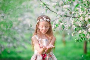 adorable niña en el floreciente jardín de manzanos el día de primavera foto