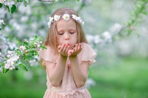 Portrait of beautiful little girl in blooming apple tree garden on spring day photo