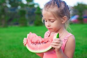 Little girl eating a ripe juicy watermelon in summertime photo