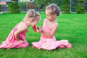 Little adorable girls eating a ripe juicy watermelon in summertime photo