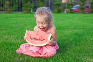 Little girl eating a ripe juicy watermelon in summertime photo