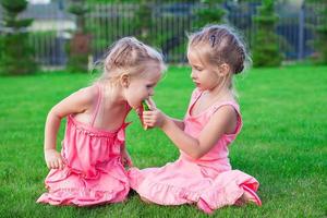 Older sister feeding younger piece of watermelon on a hot summer day photo