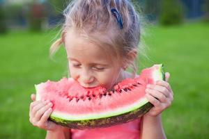 Little girl eating a ripe juicy watermelon in summertime photo