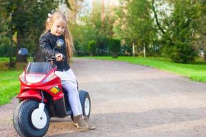 Adorable little girl having fun on her toy motorcycle photo