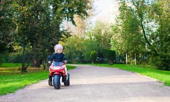 niñas adorables montando en moto para niños en el parque verde foto