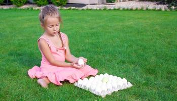 Little beautiful girl is preparing for Easter with a tray of white eggs photo