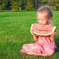 Little girl eating a ripe juicy watermelon in summertime photo