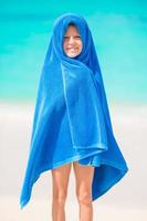 Adorable little girl wrapped in towel at tropical beach after swimming in the sea photo