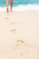 Human footprints on the white sandy beach photo