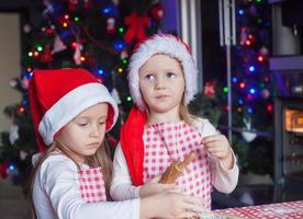 dos niñas hacen galletas de jengibre para navidad en casa foto