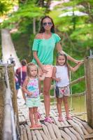 Young mother with her little girls on suspension bridge over the River photo