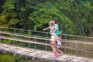 Young mother with her little girls on suspension bridge over the River photo