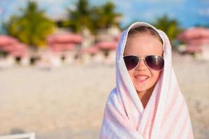 Portrait of little girl covered with towel at tropical beach photo