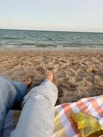 mujer feliz disfrutando de la hermosa puesta de sol en la playa. primer plano de las piernas en la arena foto