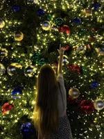 Young girl on the background of the Christmas tree in Miami. Beautiful Christmas Tree at the popular area at Xmas eve and lights photo