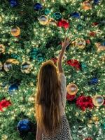 Young girl on the background of the Christmas tree in Miami. Beautiful Christmas Tree at the popular area at Xmas eve and lights photo