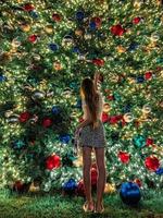 niña en el fondo del árbol de navidad en miami. hermoso árbol de navidad en la zona popular en la víspera de navidad y luces foto