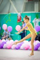 Little beautiful gymnast on carpet. Adorable gymnast participates in competitions in rhythmic gymnastics photo