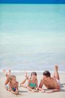 padre e hijos pequeños disfrutando de las vacaciones tropicales de verano en la playa. familia jugando en la playa foto