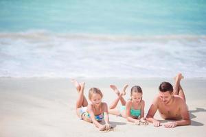 padre e hijos pequeños disfrutando de las vacaciones tropicales de verano en la playa. familia jugando en la playa foto