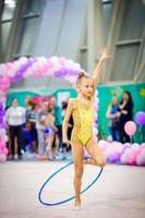 pequeña y hermosa gimnasta en la alfombra. adorable gimnasta participa en competiciones de gimnasia rítmica foto