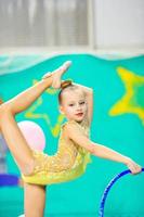 Little beautiful gymnast in competitions of rhythmic gymnastics photo