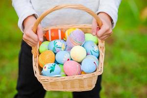 Cesta de primer plano llena de coloridos huevos de Pascua en manos de los niños foto