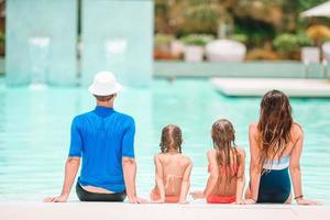 familia feliz de cuatro en la piscina al aire libre foto