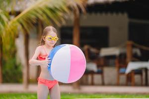 adorable niña sonriente jugando con una pelota de juguete inflable en la piscina al aire libre foto