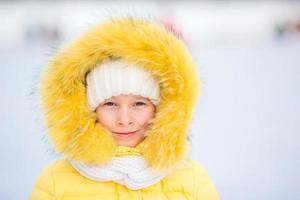 Portrait of little adorable girl with beautiful green eyes in snow sunny winter day photo