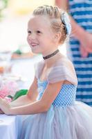 Adorable little girl in amazing dress at a wedding ceremony outdoors photo