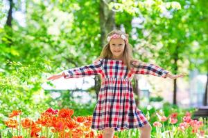 niña hermosa en el jardín de tulipanes en el cálido día de primavera foto