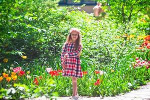 niña adorable con flores en el jardín de tulipanes foto