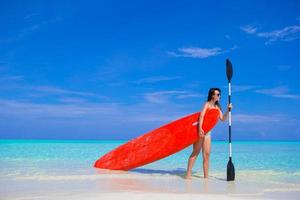 Happy young surf woman at the beach with a surfboard and paddle photo